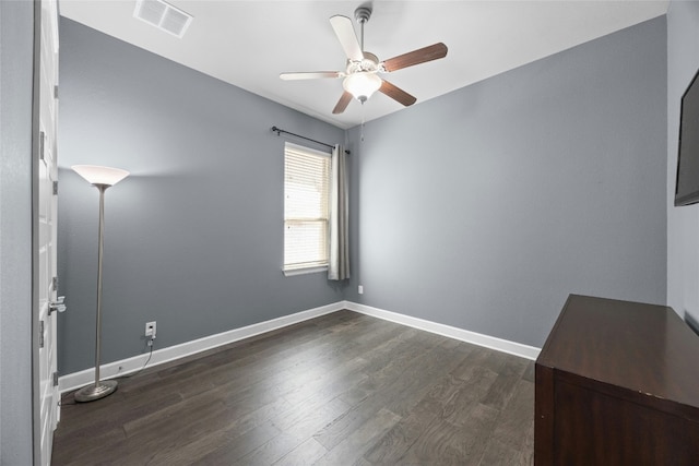 empty room featuring baseboards, visible vents, dark wood finished floors, and a ceiling fan