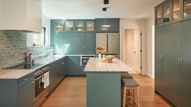 kitchen featuring light wood finished floors, premium appliances, a breakfast bar area, a center island, and a sink