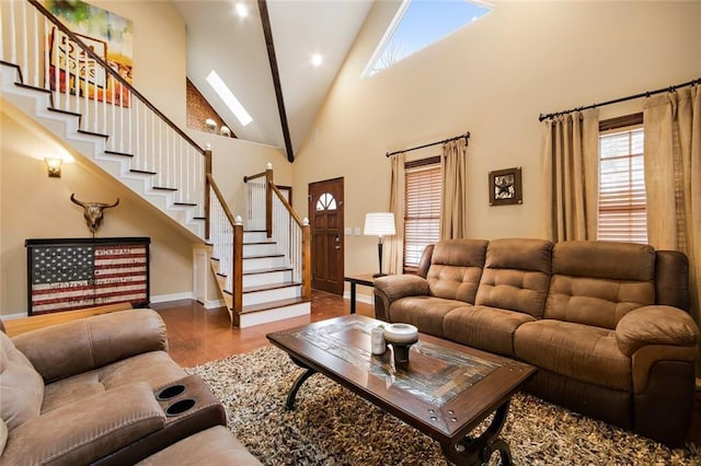 living room with a skylight, baseboards, stairway, wood finished floors, and high vaulted ceiling