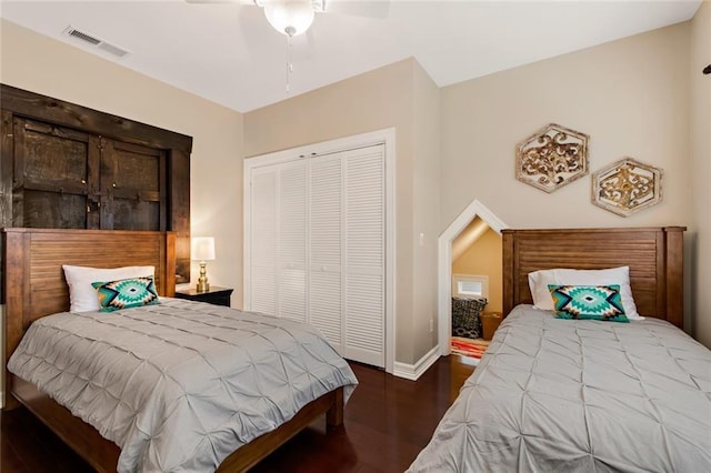 bedroom with ceiling fan, wood finished floors, visible vents, baseboards, and a closet