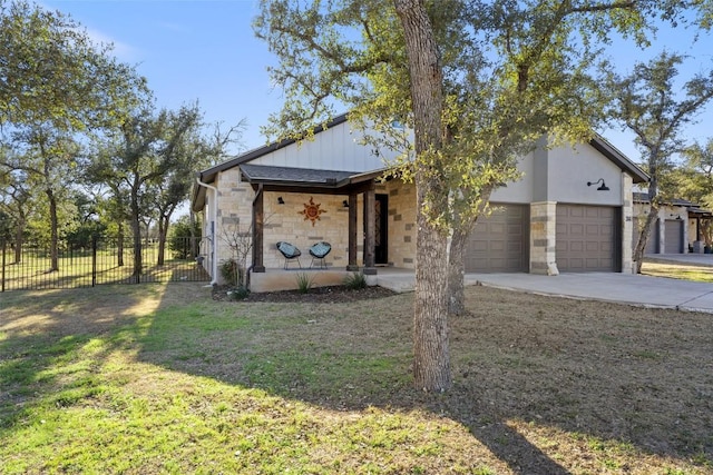 view of front of property with driveway, stone siding, an attached garage, fence, and a front lawn