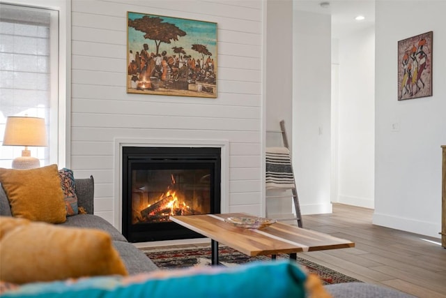 interior space with recessed lighting, baseboards, wood finished floors, and a glass covered fireplace