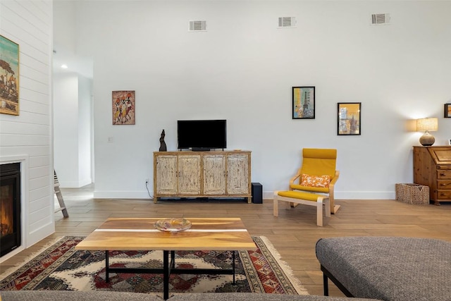 living area featuring a large fireplace, wood finished floors, and visible vents