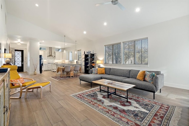 living area with high vaulted ceiling, recessed lighting, a ceiling fan, a healthy amount of sunlight, and light wood-type flooring