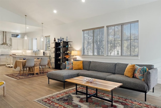 living room featuring lofted ceiling, recessed lighting, visible vents, and light wood-style floors