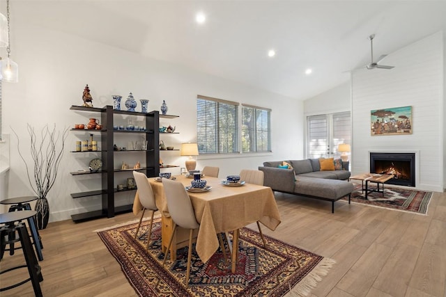 dining space featuring light wood-style flooring, recessed lighting, a fireplace, a ceiling fan, and vaulted ceiling