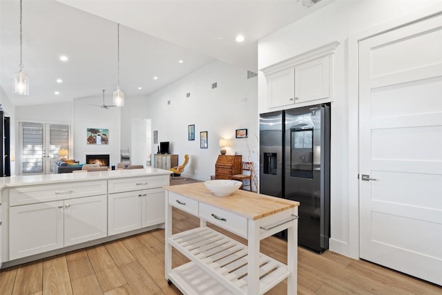 kitchen with a large fireplace, white cabinets, open floor plan, light wood-style floors, and stainless steel refrigerator with ice dispenser