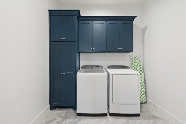 washroom with washer and dryer, cabinet space, and baseboards