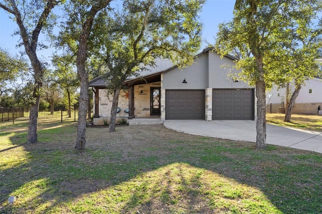 view of front of home featuring driveway, a garage, stone siding, fence, and a front lawn