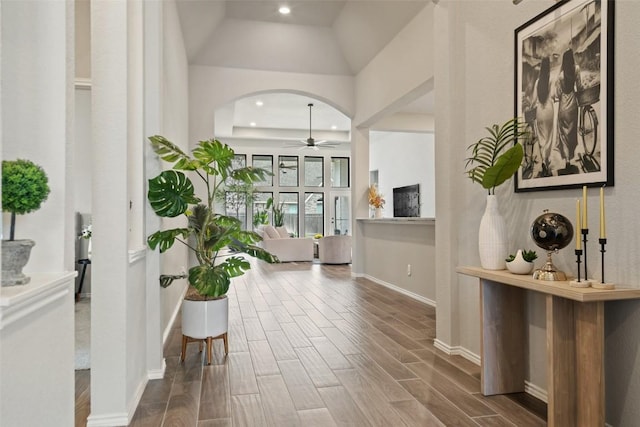 hall with wood tiled floor, arched walkways, baseboards, and recessed lighting