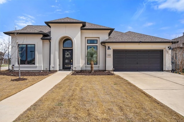 prairie-style home featuring concrete driveway, a shingled roof, an attached garage, and stucco siding