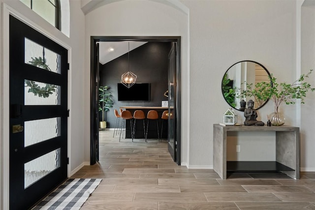 entryway featuring wood finish floors, a high ceiling, and baseboards