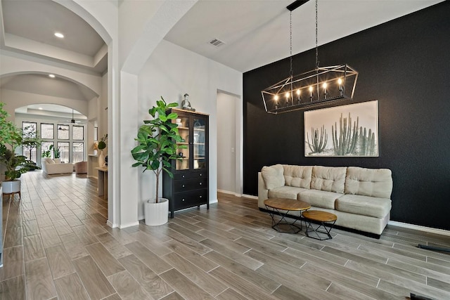 living room with an accent wall, visible vents, and wood finish floors