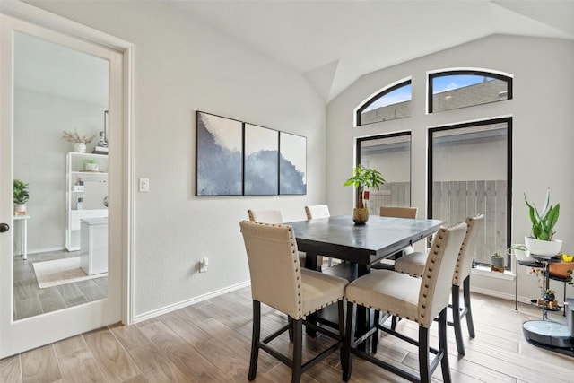 dining area with baseboards, vaulted ceiling, and wood finished floors