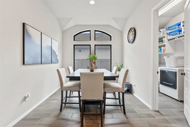 dining space featuring wood tiled floor, washer / clothes dryer, vaulted ceiling, and baseboards