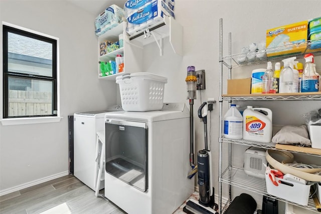 laundry room with laundry area, baseboards, washer and dryer, and wood finished floors