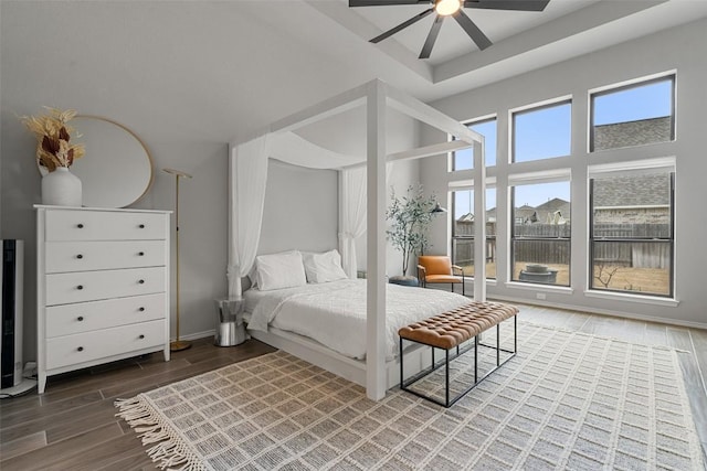 bedroom featuring a ceiling fan, wood finish floors, a towering ceiling, and baseboards