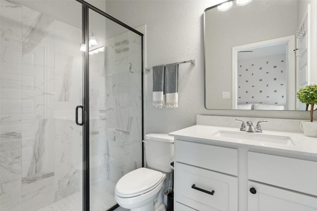 ensuite bathroom featuring toilet, a textured wall, vanity, and a marble finish shower