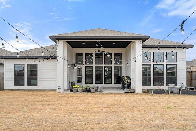 back of house featuring a shingled roof and a lawn