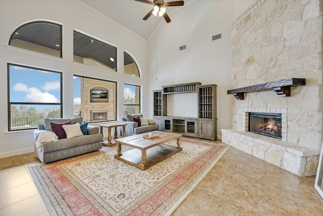 tiled living room with ornamental molding, visible vents, a stone fireplace, and baseboards