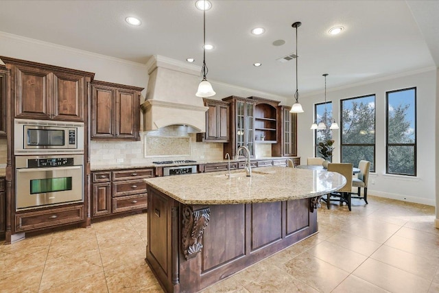 kitchen with stainless steel appliances, visible vents, decorative backsplash, a sink, and premium range hood