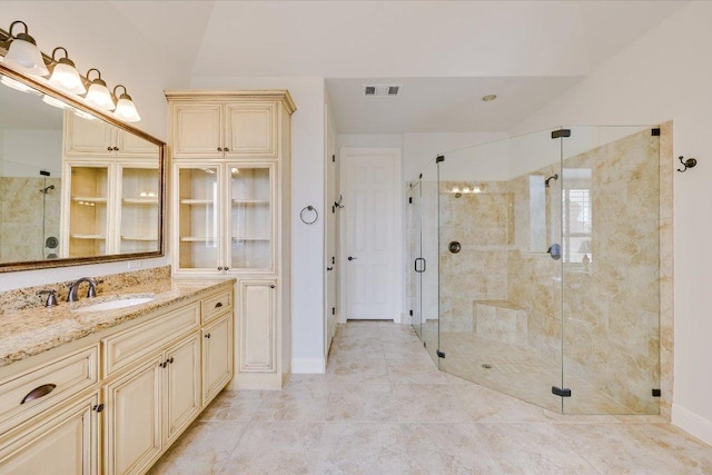 bathroom with lofted ceiling, vanity, visible vents, baseboards, and a shower stall