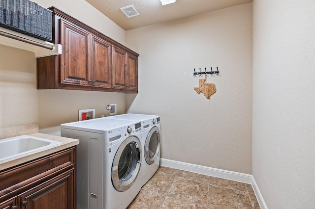 washroom with visible vents, washer and clothes dryer, cabinet space, and baseboards