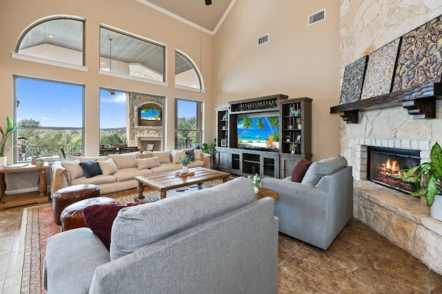 living area with high vaulted ceiling, visible vents, crown molding, and a stone fireplace