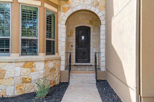 view of exterior entry with stone siding and stucco siding