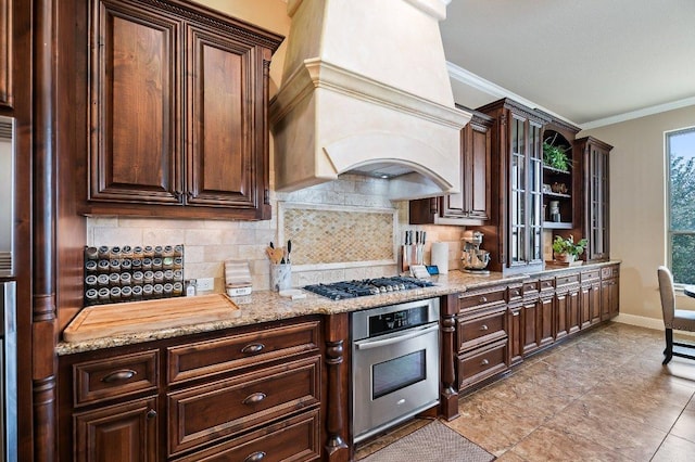 kitchen featuring premium range hood, ornamental molding, stainless steel appliances, and decorative backsplash