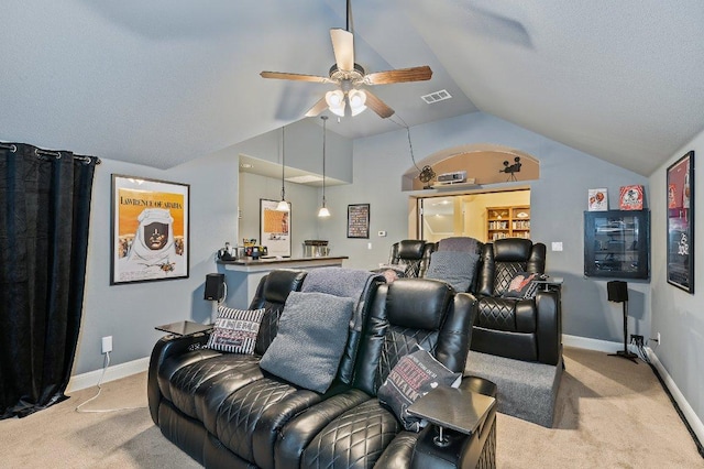 cinema room featuring light carpet, lofted ceiling, visible vents, and baseboards