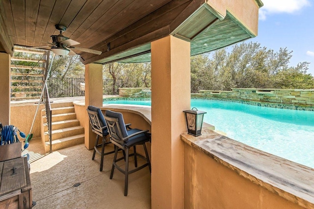 view of patio with ceiling fan, fence, and an outdoor pool