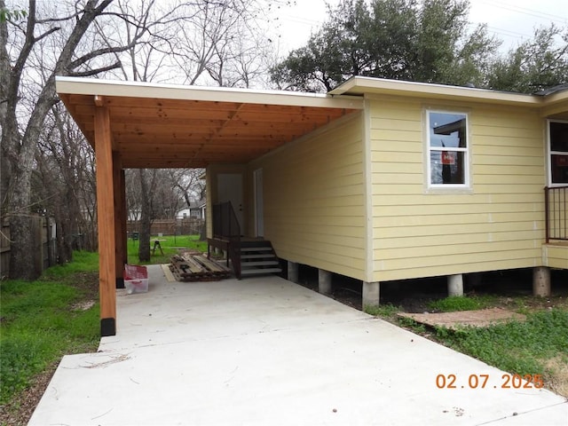 view of side of home featuring entry steps, concrete driveway, and an attached carport