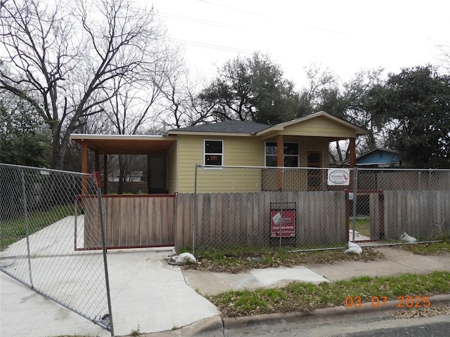 bungalow-style home featuring an attached carport, a fenced front yard, and a gate