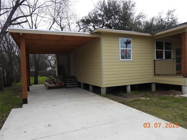 view of side of home featuring entry steps, concrete driveway, and a carport