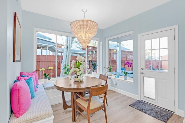 dining area featuring baseboards, light wood-style flooring, and a notable chandelier