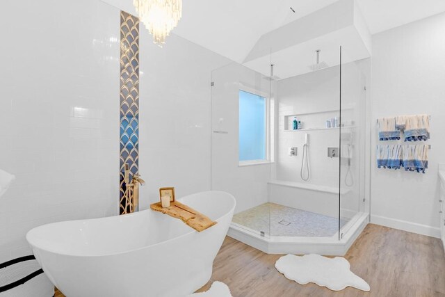 bathroom with wood finished floors, a sink, vaulted ceiling, a soaking tub, and a shower stall