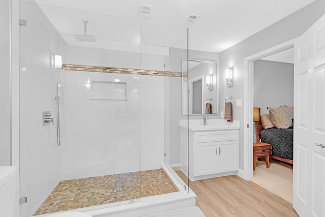 bathroom featuring toilet, wood finished floors, vanity, a shower stall, and ensuite bath