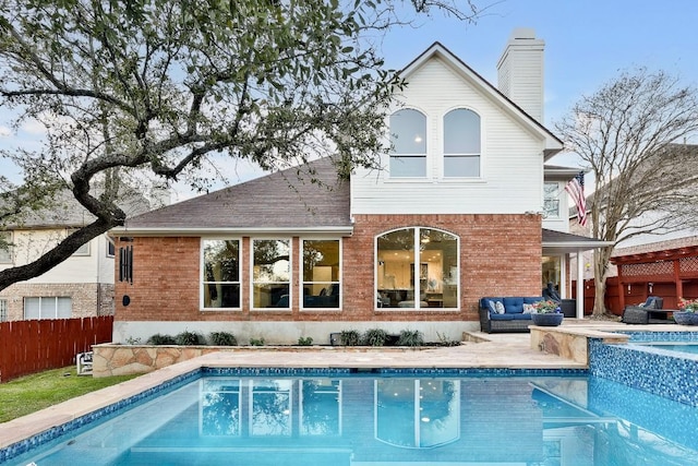 back of property with a fenced in pool, a chimney, fence, an outdoor living space, and brick siding