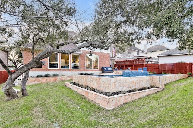 rear view of house featuring a yard, fence, and brick siding