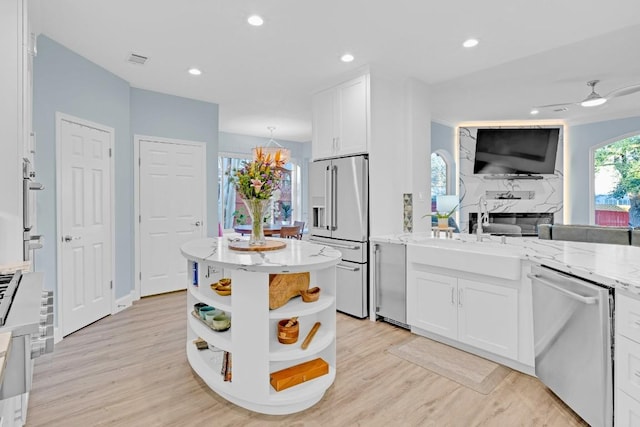 kitchen with appliances with stainless steel finishes, white cabinetry, light stone counters, and open shelves