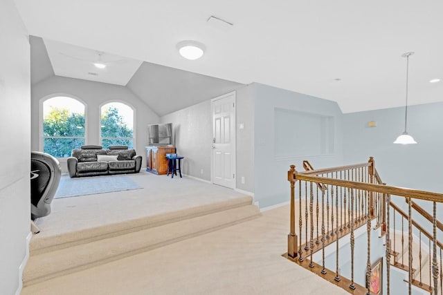 interior space with a ceiling fan, carpet flooring, vaulted ceiling, and baseboards