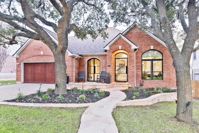 view of front of house featuring a porch, an attached garage, brick siding, a shingled roof, and concrete driveway