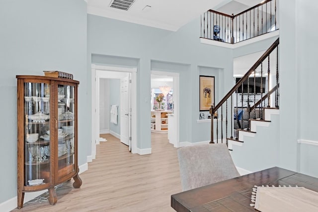 foyer entrance with light wood-type flooring, baseboards, stairs, and visible vents