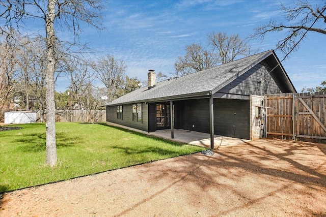 back of house featuring roof with shingles, a chimney, a lawn, a patio area, and fence