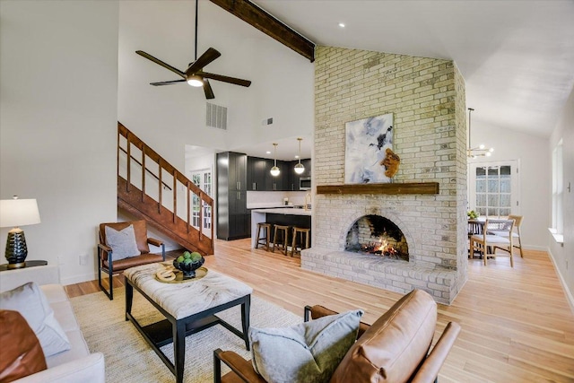 living room with baseboards, visible vents, light wood-style flooring, beamed ceiling, and a fireplace