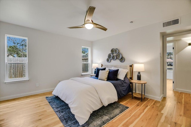 bedroom featuring baseboards, multiple windows, visible vents, and light wood-style floors