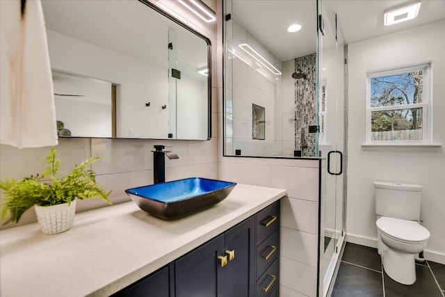 bathroom featuring a stall shower, toilet, tile patterned flooring, vanity, and tile walls