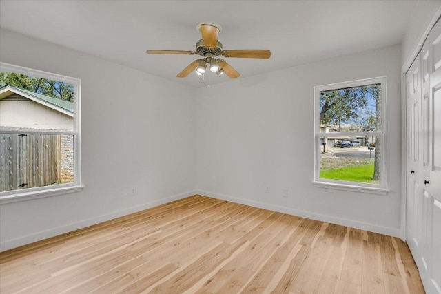 unfurnished room featuring light wood finished floors, baseboards, and a ceiling fan