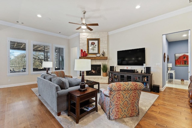 living room with baseboards, light wood-type flooring, a fireplace, and crown molding